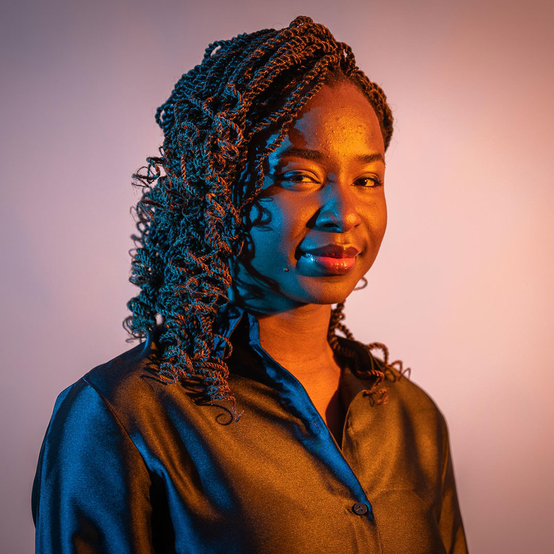 Headshot of Chinenye Okonkwo backlit with purple light