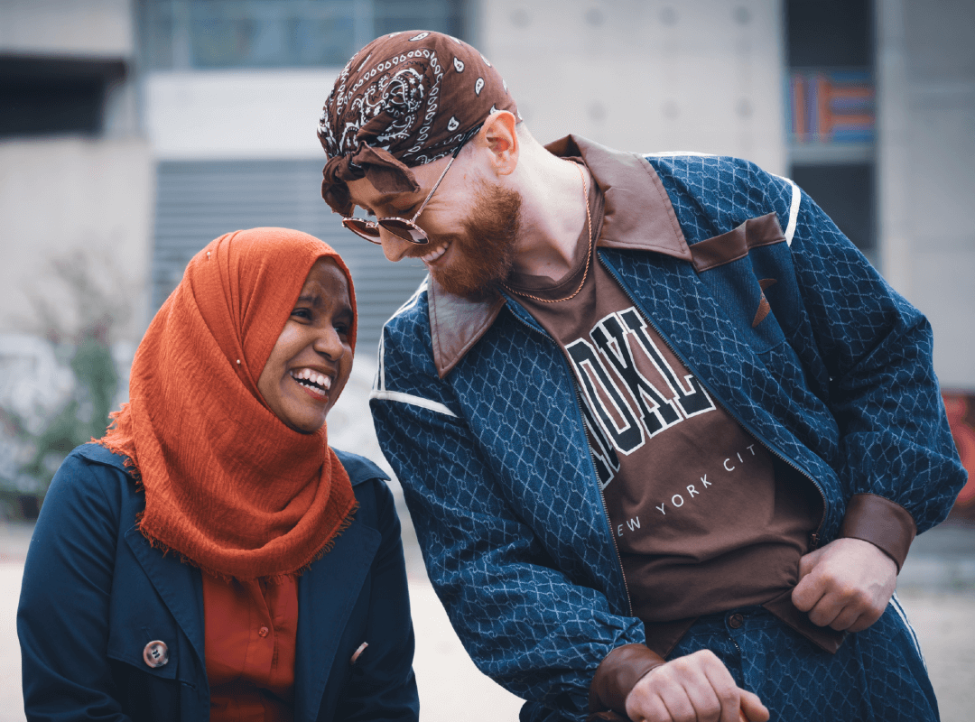 Two students leaning in to each other and laughing