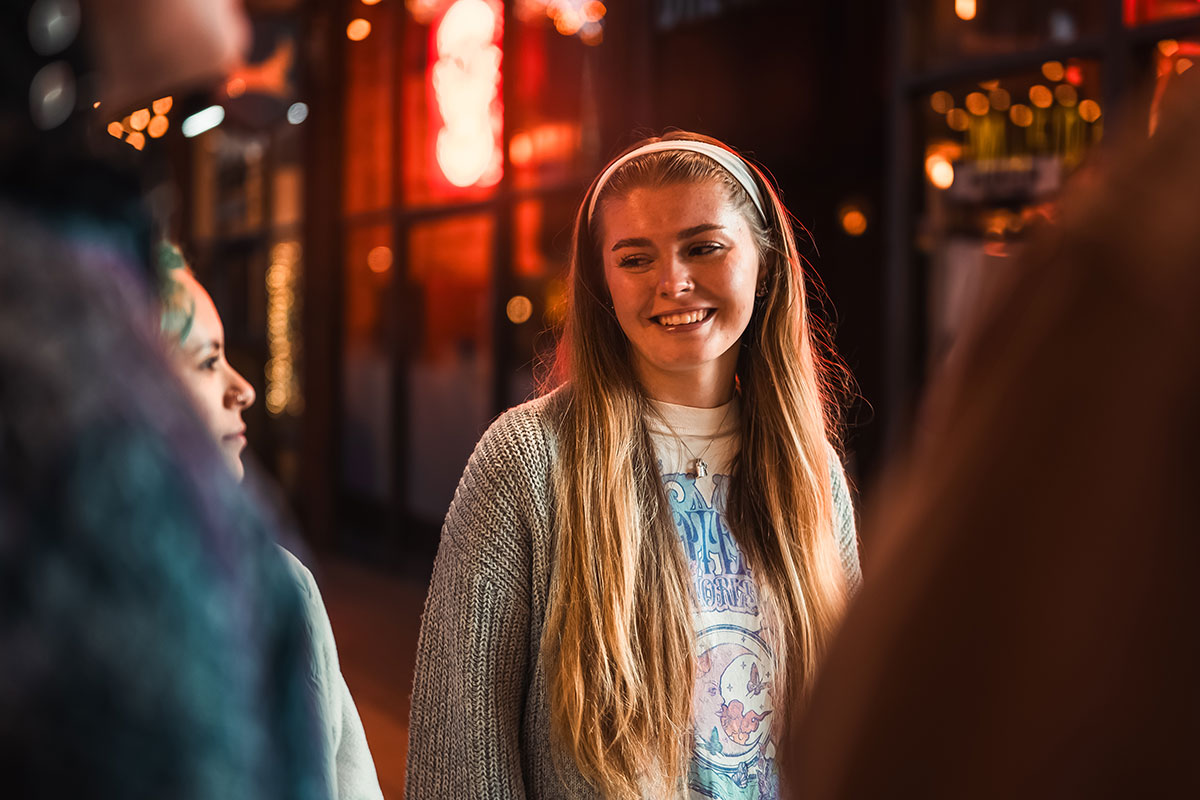 Student looking at her friend and smiling as they stand in a small group.